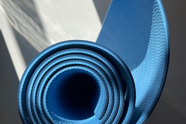 Person stretching on a mat in a bright, clean environment.